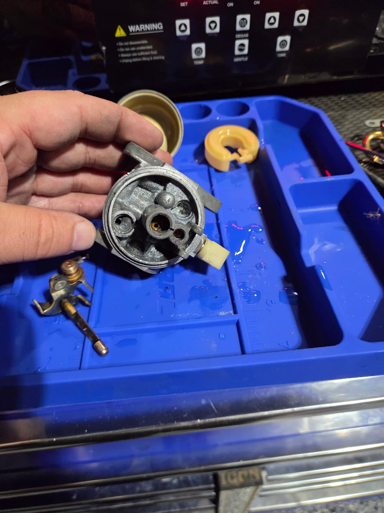 A cleaned carburetor body held up to the light