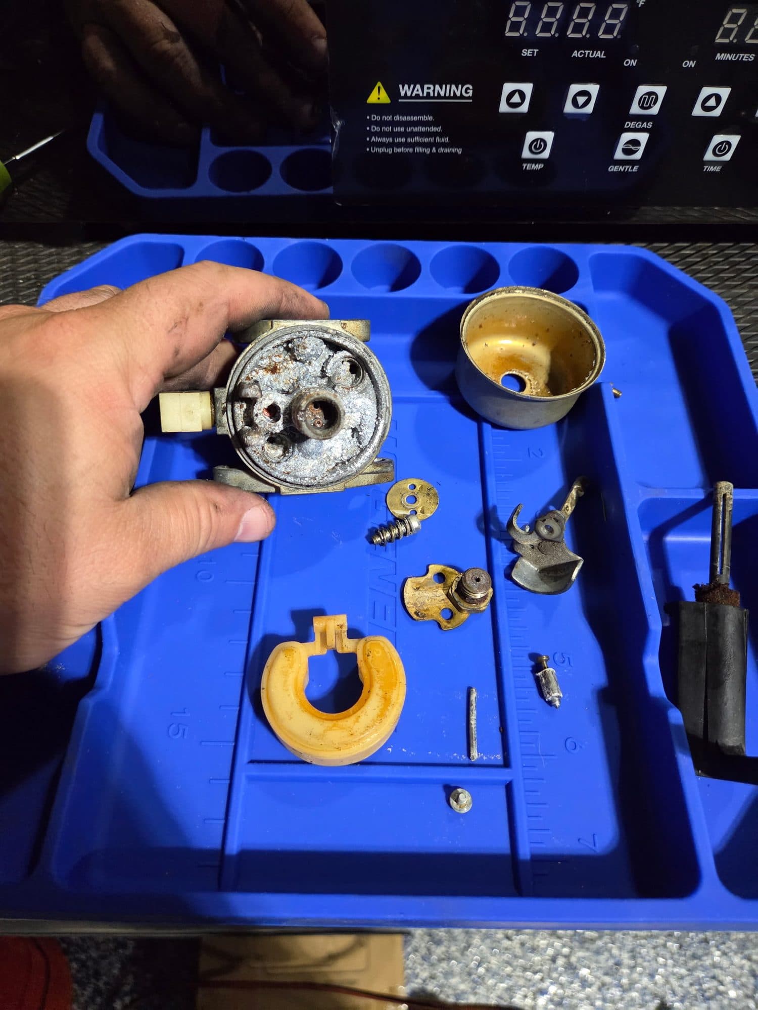Jimmy holding a carburetor body over the parts tray